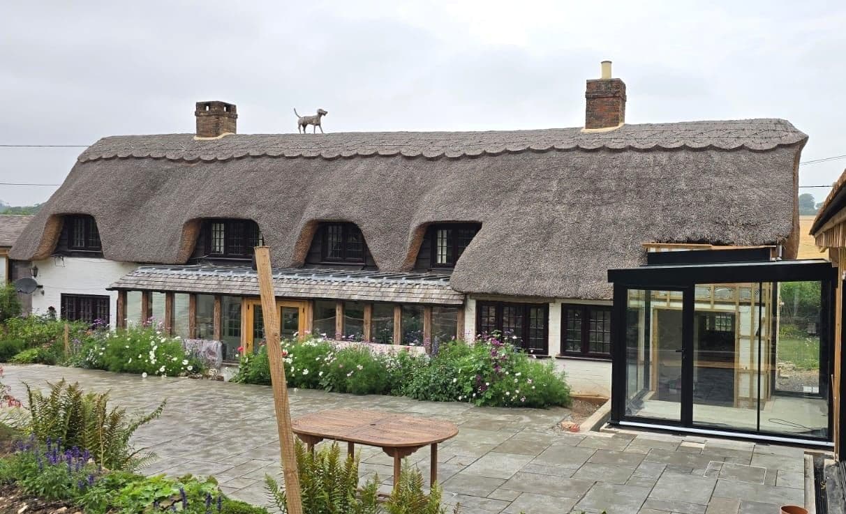 Frameless structural glass extension on a thatched period cottage
