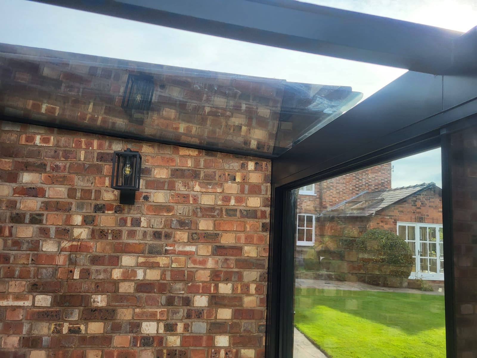 Frameless glass box extension on a home, shown from the garden